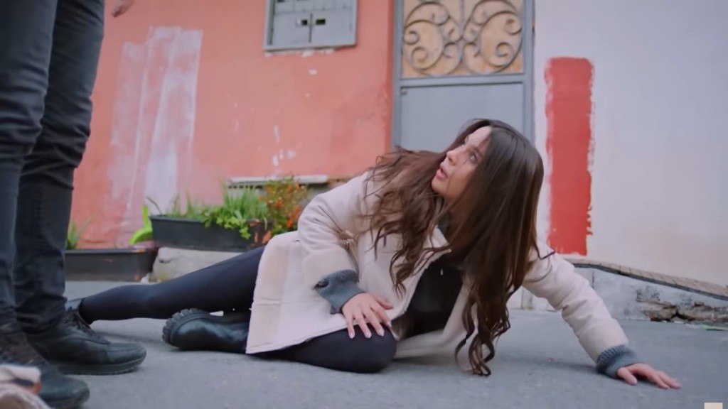 Zeynep przewróciła się na chodnik. Patrzy przestraszonym wzrokiem na stojącego przed nią mężczyznę.