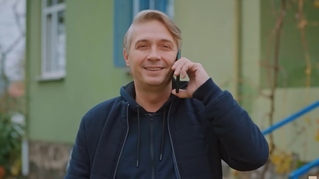 Tahir śmieje się, trzymając telefon przy uchu.