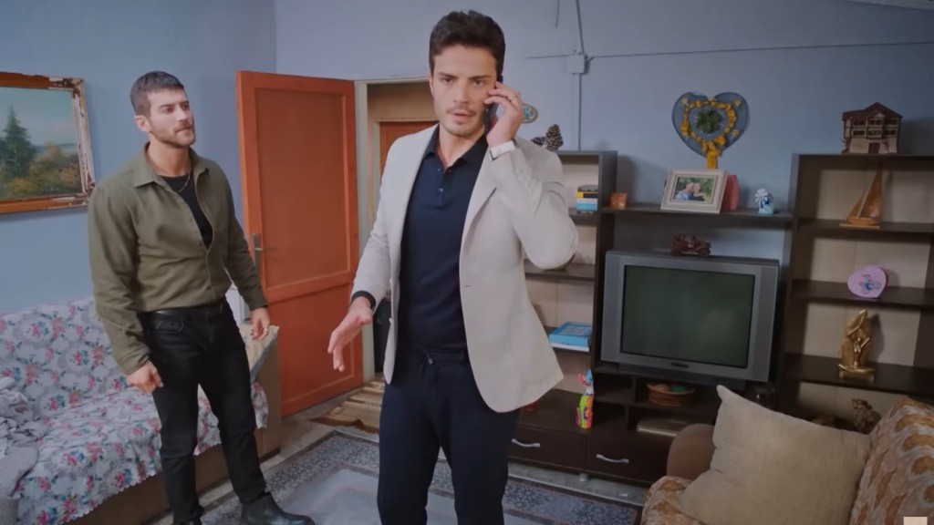 Ege rozmawia przez telefon. Obok niego stoi Cihan.