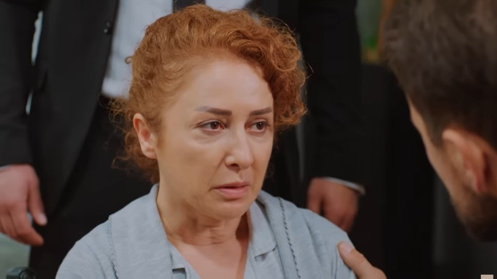 Siedząca na wózku inwalidzkim Hulya patrzy na kucającego przed nią brata. Jej twarz jest blada.