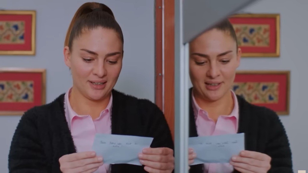 Yildiz stoi przy szafie w pokoju Cavidan i trzyma w rękach zdjęcia.