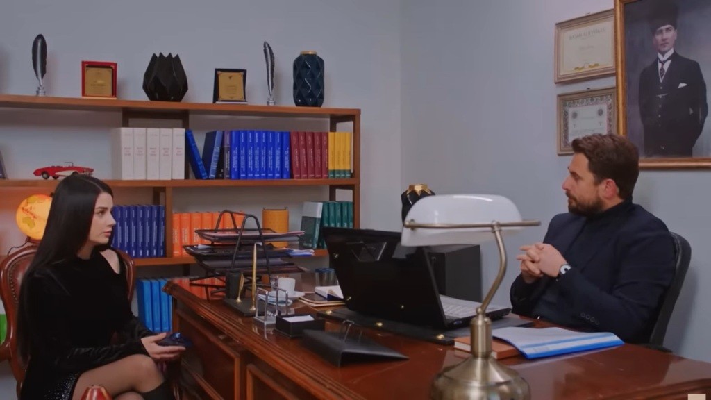 Bahar i Kuzey siedzą naprzeciwko siebie przy biurku.