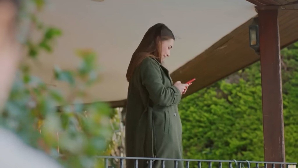 Sila stoi na werandzie i z uśmiechem patrzy w ekran telefonu.