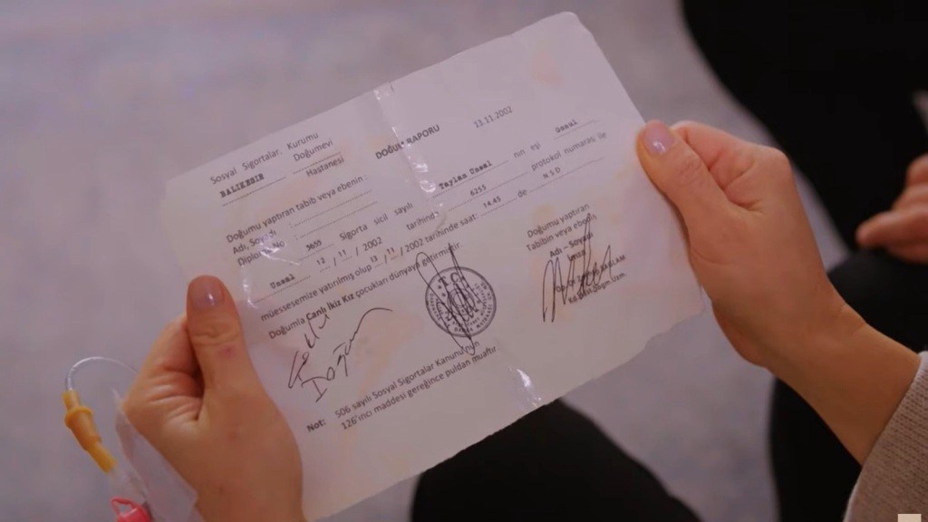 Zbliżenie na treść raportu urodzenia w rękach Gonul. Dokument mówi, że Gonul urodziła dwie żywe dziewczynki.