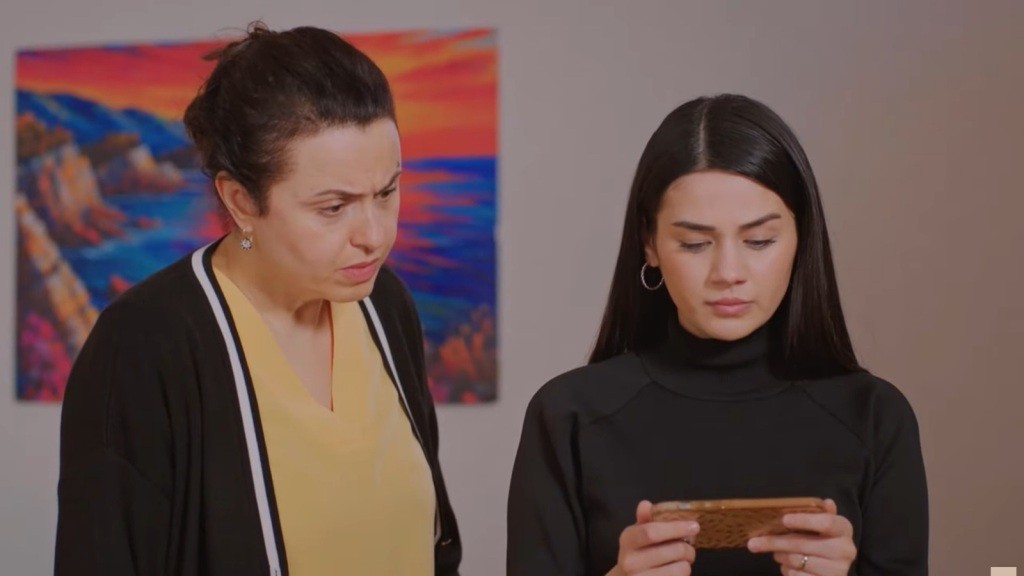 Bahar i Cavidan patrzą w ekran telefonu.