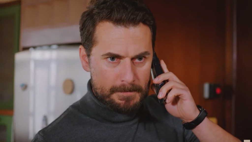 Kuzey trzyma telefon przy uchu i marszczy brwi.