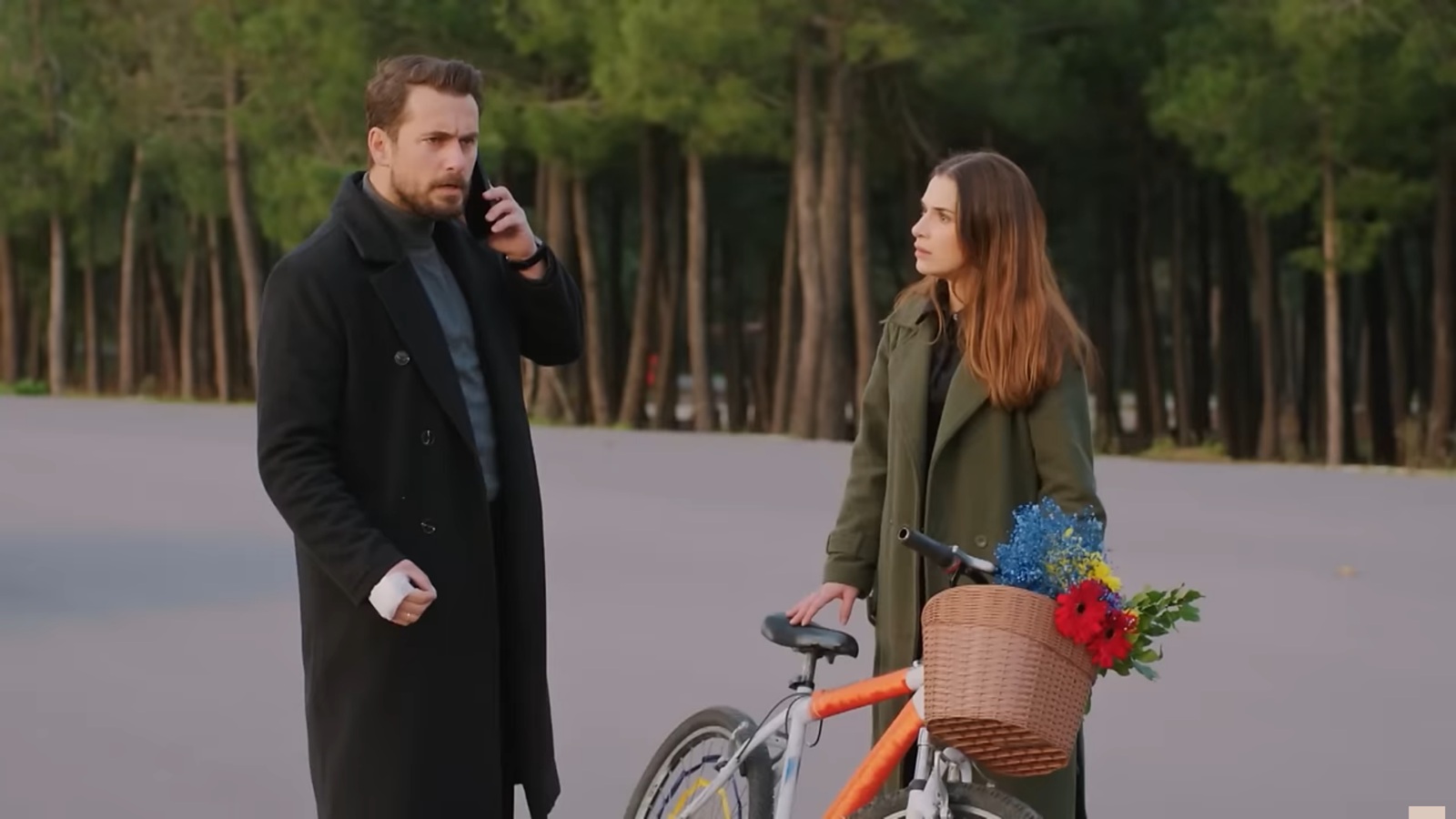 Sila opiera się o rower i z niepokojem patrzy na rozmawiającego przez telefon Kuzeya.