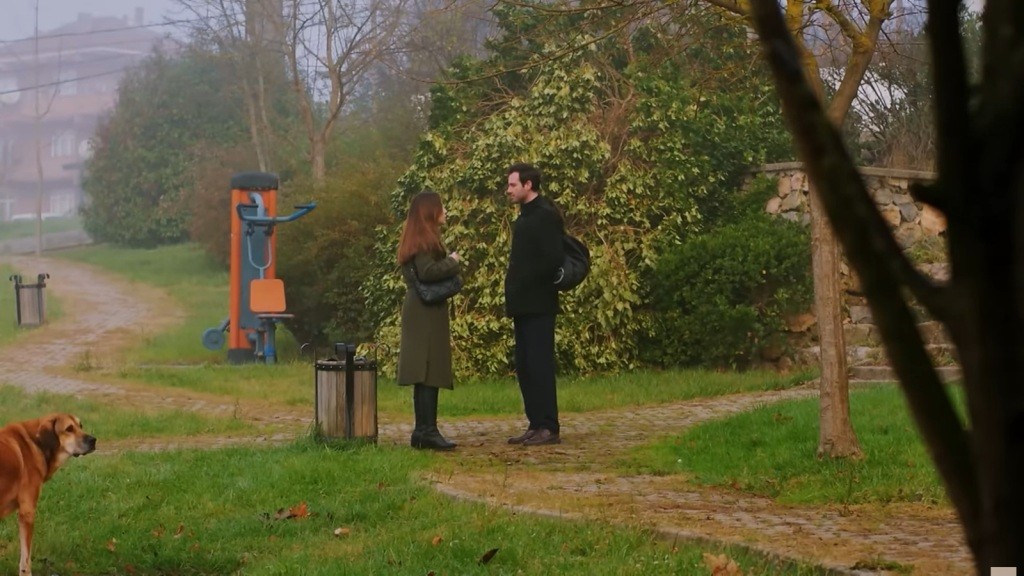 Sila i Levent stoją w parku obok kosza na śmieci.