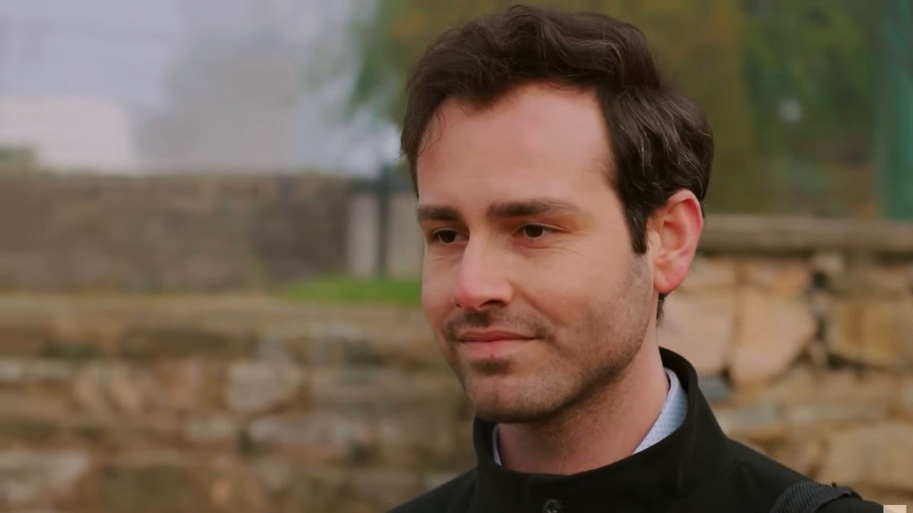 Levent unosi kąciki ust w kpiącym uśmiechu.