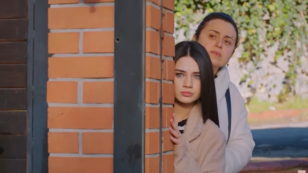 Bahar i Cavidan wychylają głowy zza ogrodzenia.