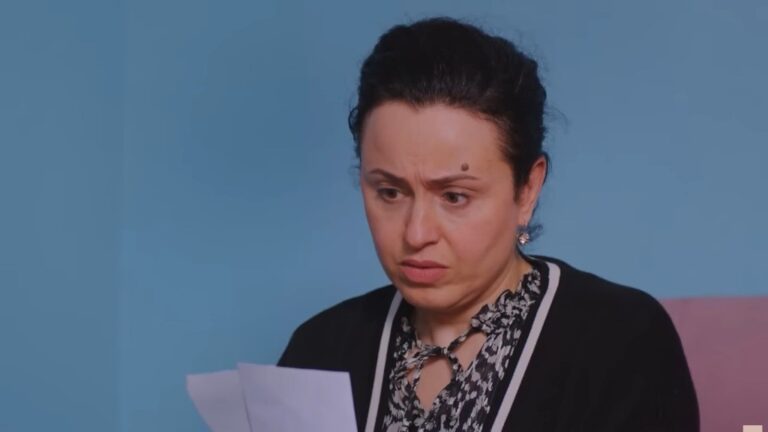 Cavidan wpatruje się w dwie fotografie.