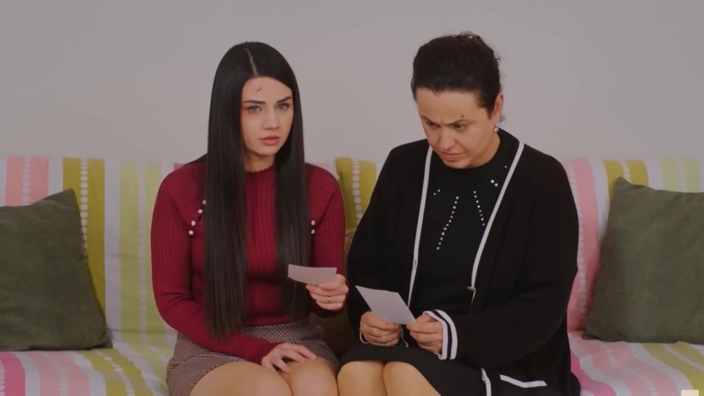 Bahar i Cavidan siedzą na kanapie, trzymając zdjęcia w rękach.