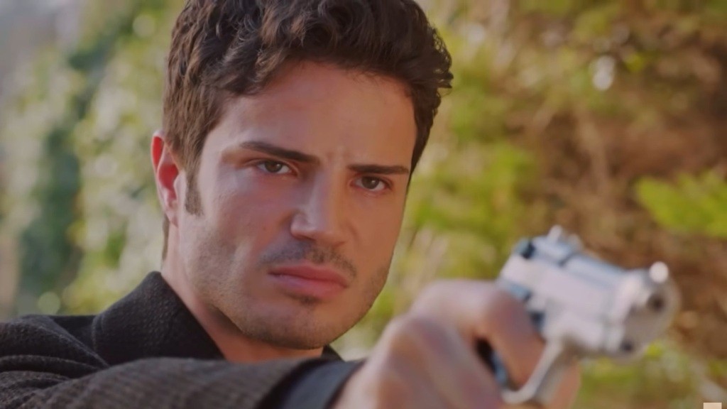 Ege trzyma w ręku pistolet i celuje przed siebie. Wyraz jego twarzy zdradza, że w każdej chwili może pociągnąć za spust.