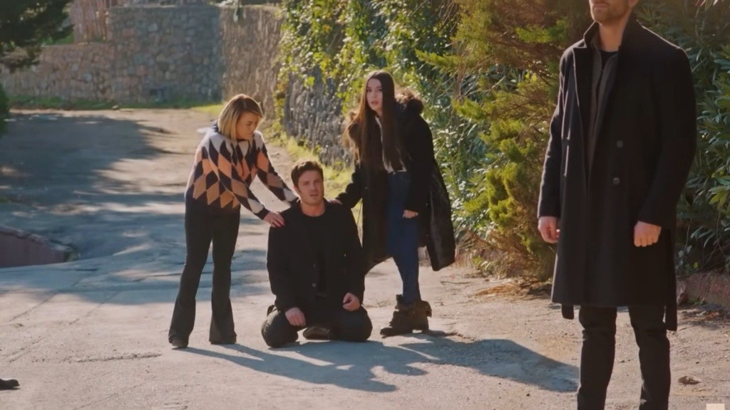 Ege upada na kolana na drodze. Obok niego stoją Belkis i Zeynep.