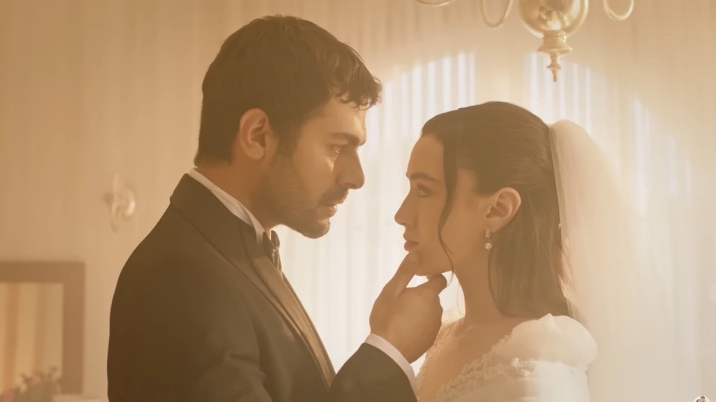 Halil stoi przed Zeynep i unosi jej podbródek. On ma na sobie garnitur, ona suknię ślubną.