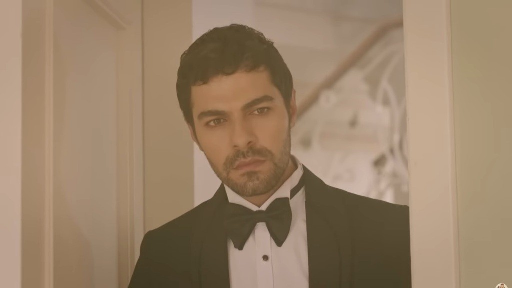 Halil, ubrany w smoking ślubny, zagląda do pokoju.