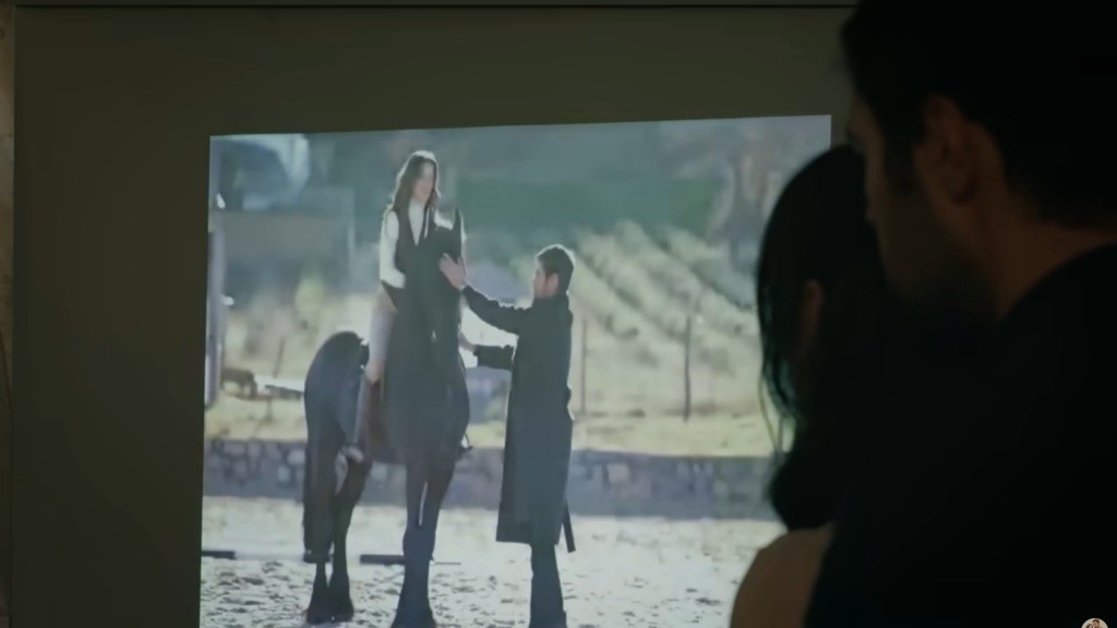 Halil i Zeynep oglądają pokaz slajdów na ekranie projekcyjnym.