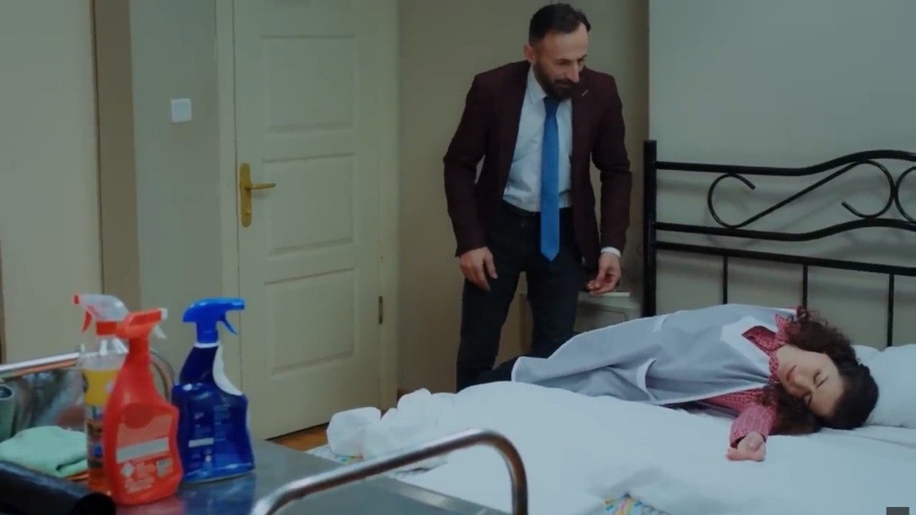 Yekta stoi nad łóżkiem, na którym leży nieprzytomna Aynur.