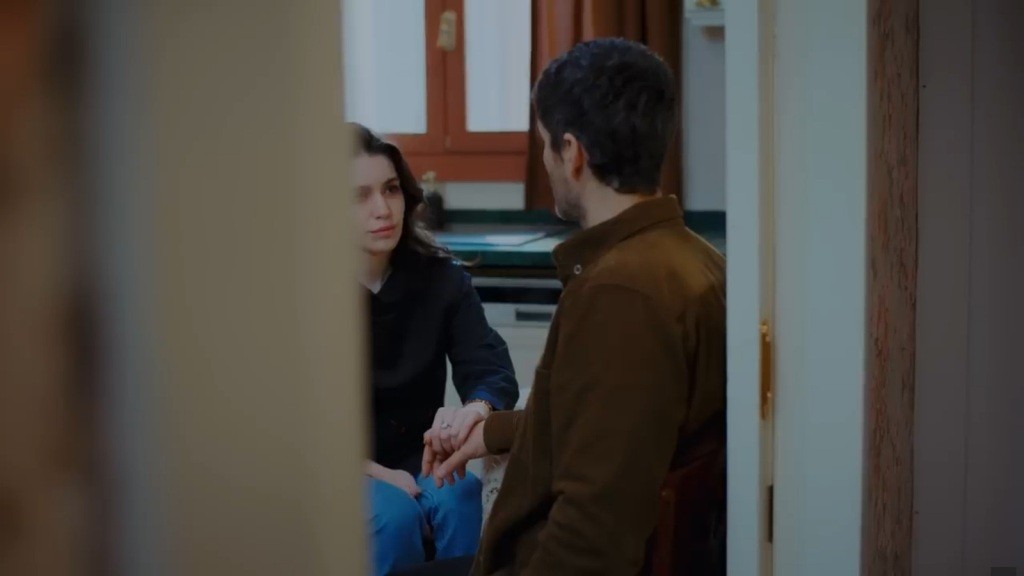 Pelin i Poyraz siedzą przy stoliku w kuchni. Pelin trzyma jego rękę.