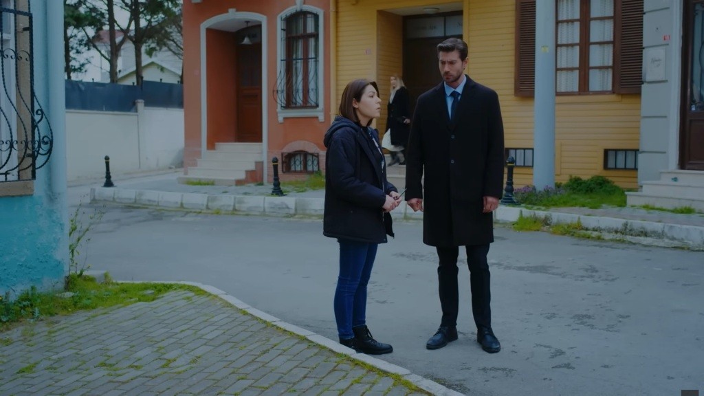 Sinan i Kara stoją na drodze, podczas gdy Isil wychodzi z budynku za ich plecami.