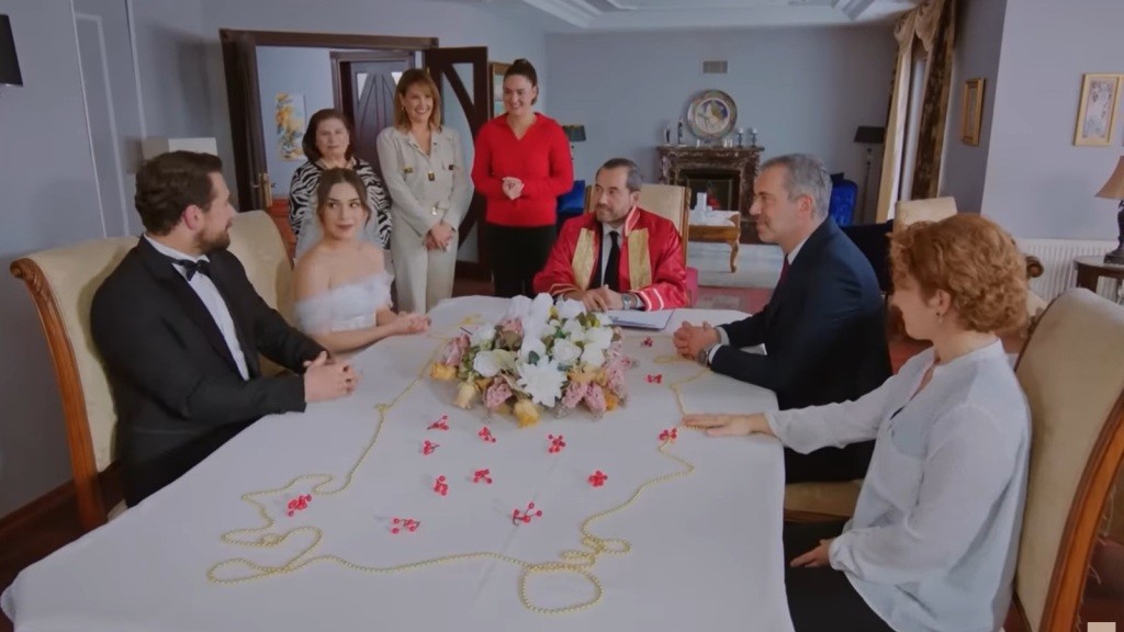 Kuzey i Sila siedzą przy stole ślubnym. Hulya i Bulent siedzą naprzeciwko nich, a urzędnik tuż obok.