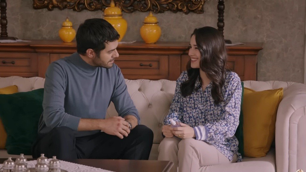 Gulhan uśmiecha się radośnie, trzymając w dłoniach perfumy i patrząc na brata.