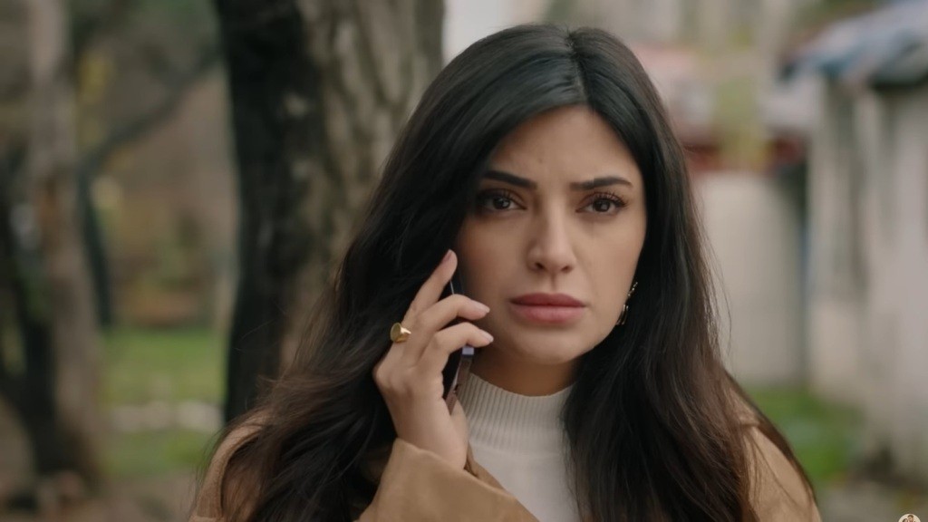 Gozde rozmawia przez telefon na zewnątrz.