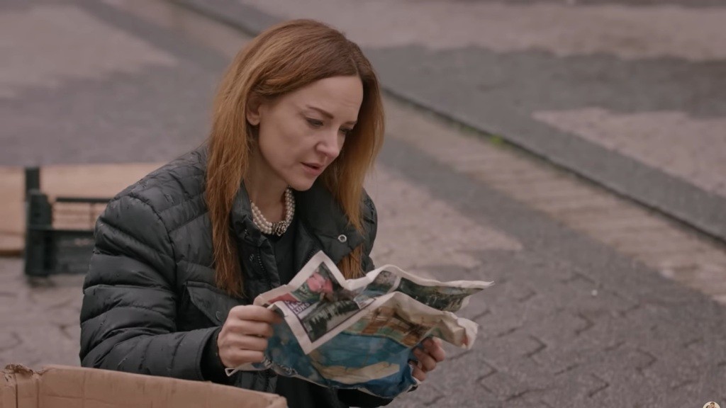 Songul rozkłada zmiętą gazetę.