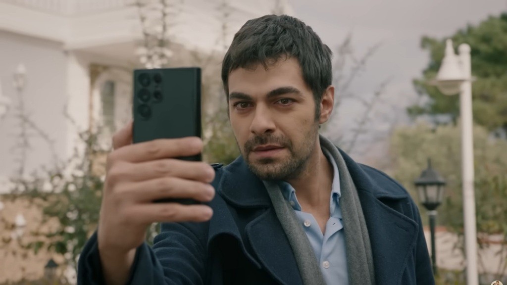 Halil patrzy w wyciągnięty przed siebie telefon.