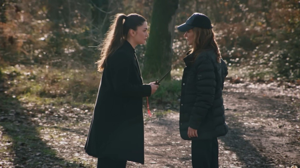 Arzu stoi przed Songul w lesie i trzyma skierowany w jej stronę sztylet.