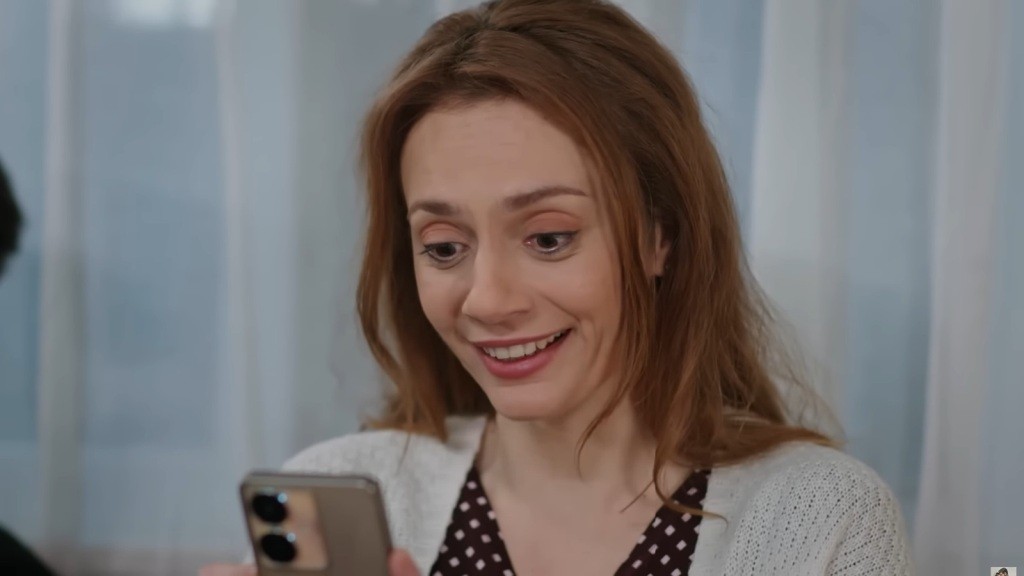 Derya jest zachwycona, patrząc w ekran telefonu.