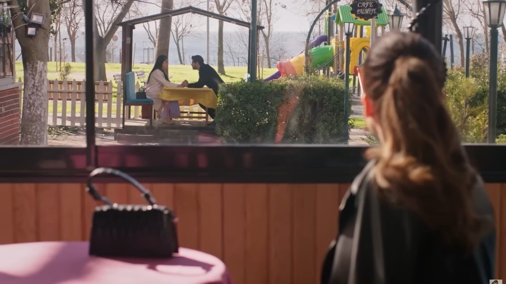 Beyza widzi, jak Cihan i Hancer trzymają się za ręce, siedząc przy stoliku.