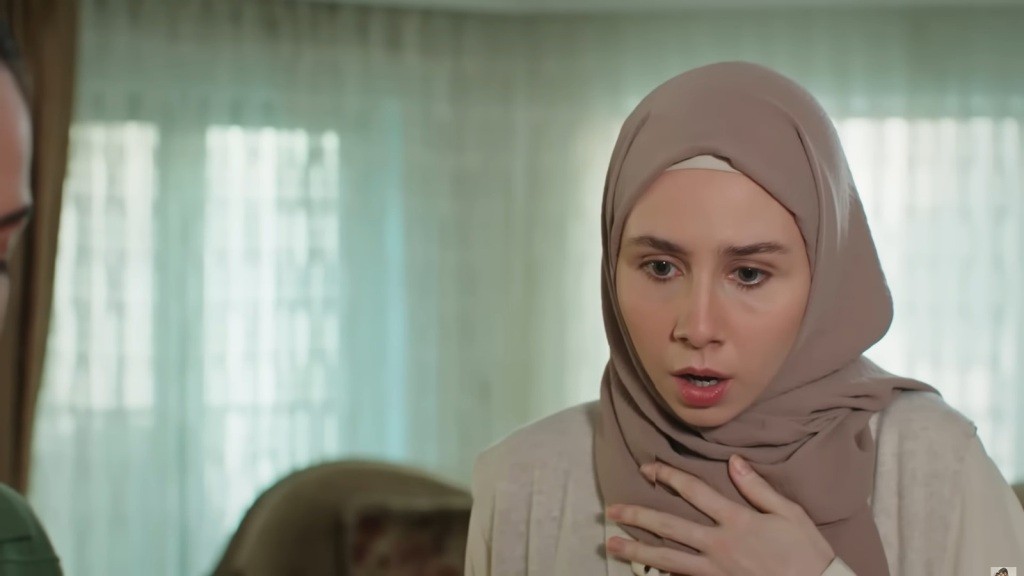 Zszokowana Sinem przykłada dłoń do piersi.