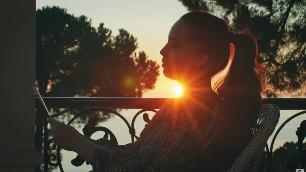 Beyza siedzi na balkonie, a zachodzące słońce pada na nią.