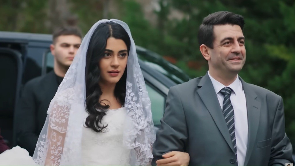 Cemil prowadzi Hancer ubraną w suknię ślubną.