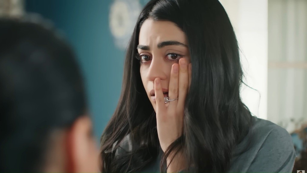 Hancer trzyma się za policzek i przestraszonym wzrokiem patrzy na Mukadder.