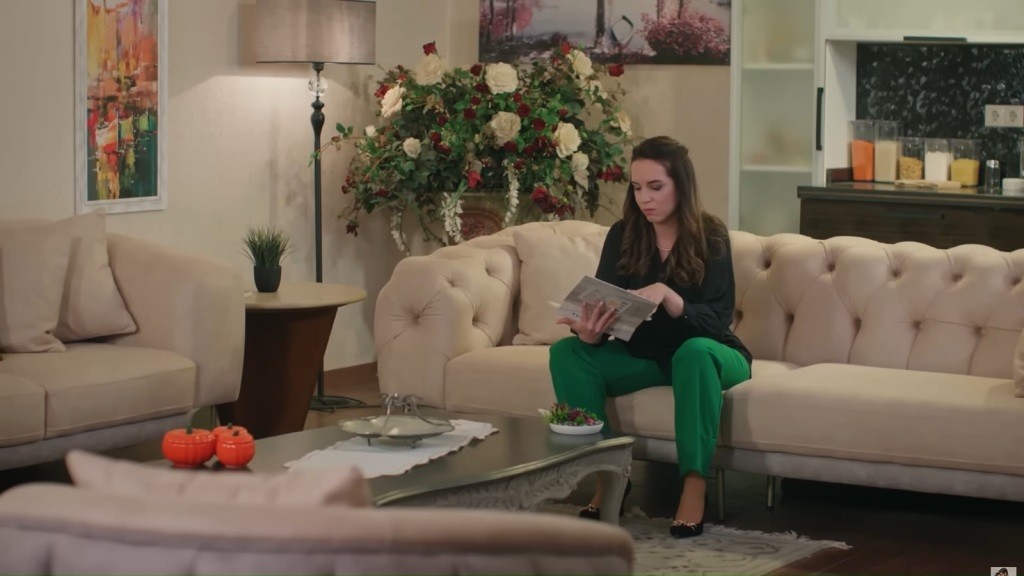Beyza siedzi na kanapie i przegląda album ze zdjęciami.