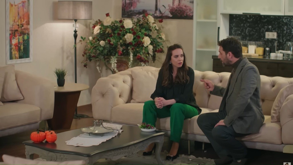 Nusret siedzi obok córki na kanapie i coś jej tłumaczy.