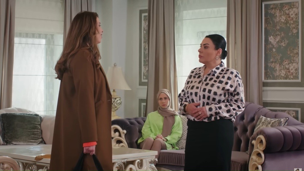 Beyza stoi przed Mukadder. Na drugim planie widać siedzącą na kanapie Sinem.