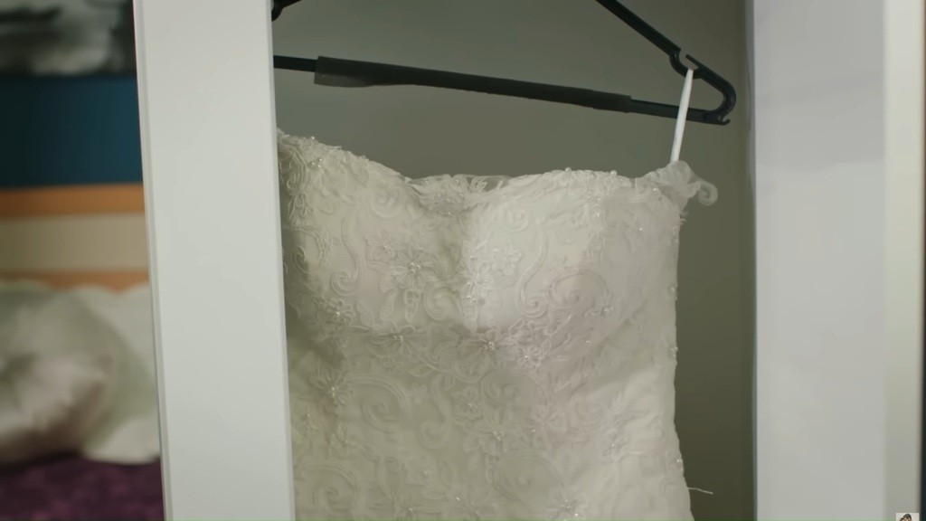 Zbliżenie na suknię ślubną wiszącą w szafie.