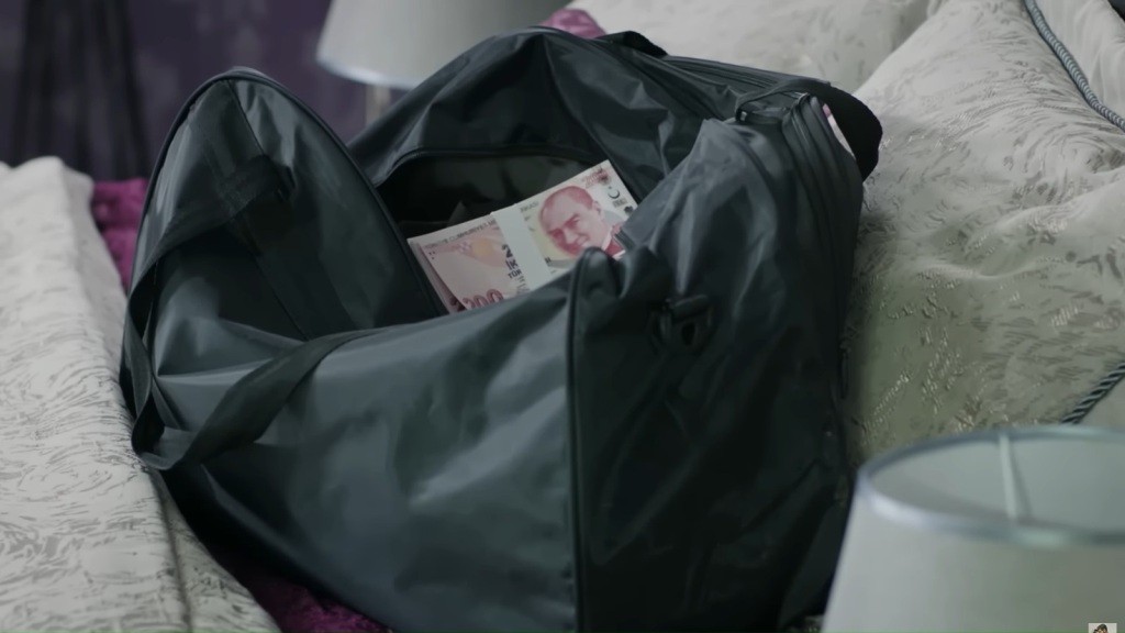 Zbliżenie na czarną torbę z pieniędzmi w środku.
