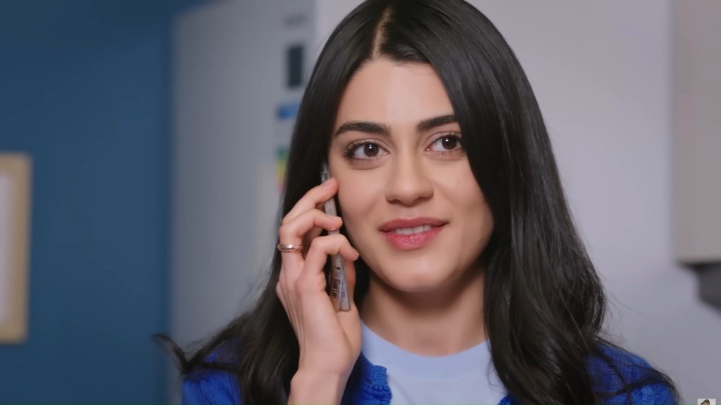 Hancer rozmawia przez telefon, uśmiechając się lekko.