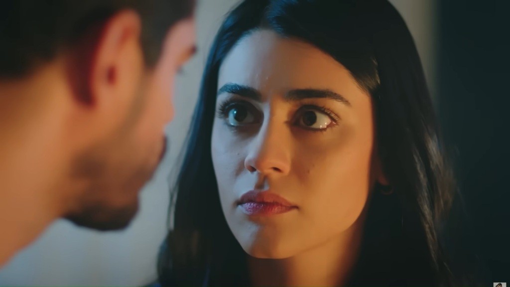 Hancer patrzy swoimi dużymi oczami w twarz Cihana. Pokój oświetlany jest przez ciepłe światło świecy.