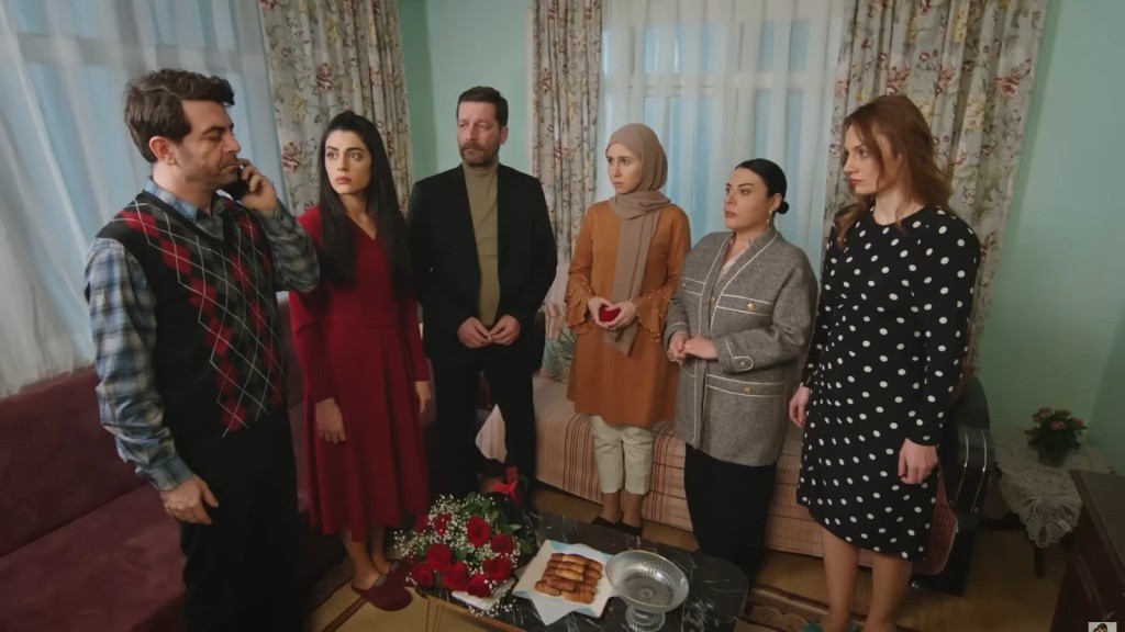 Cemil rozmawia przez telefon, a pozostali wpatrują się w niego z poważnymi twarzami.