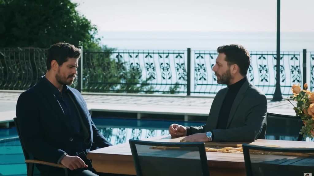 Cihan i Nusret siedzą przy stoliku obok basenu.