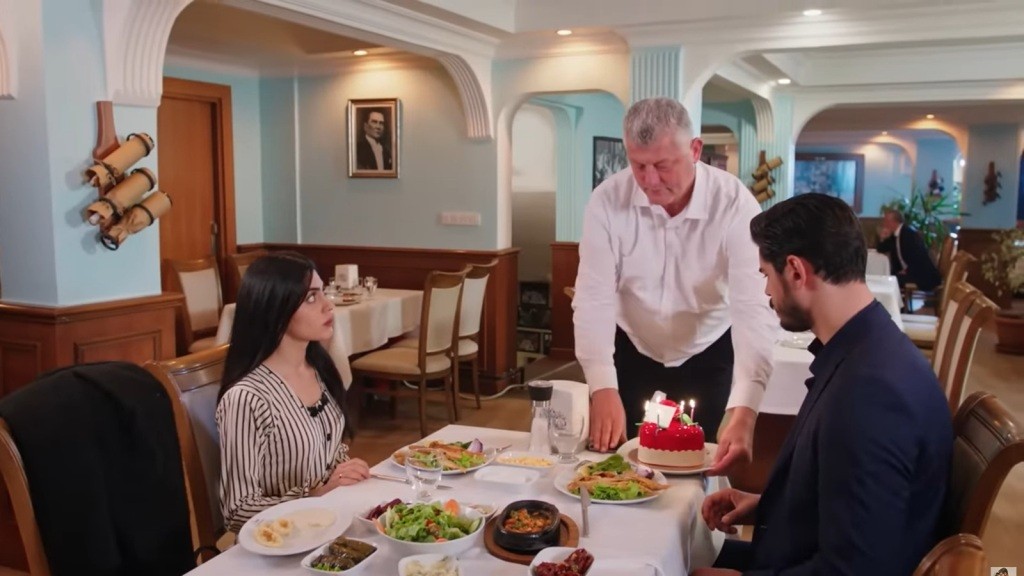 Kelner przynosi tort do stolika Cihana i Hancer.