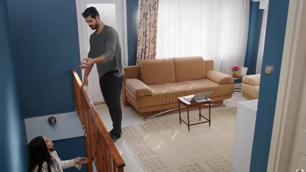 Hancer stoi w połowie schodów i patrzy na stojącego przy balustradzie Cihana.