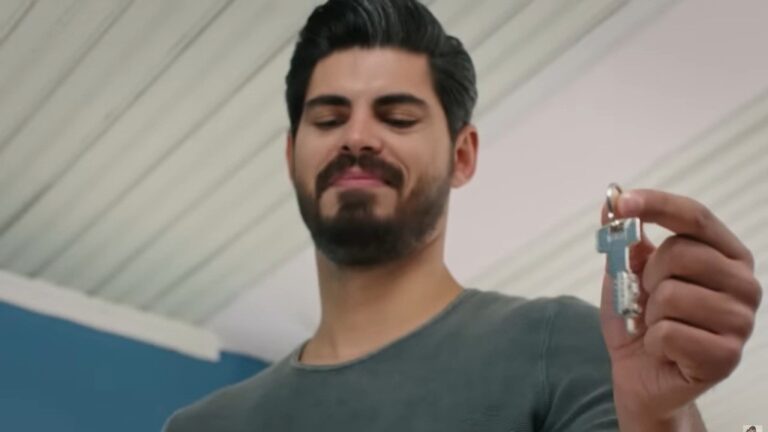 Cihan trzyma klucz w palcach. Uśmiecha się.