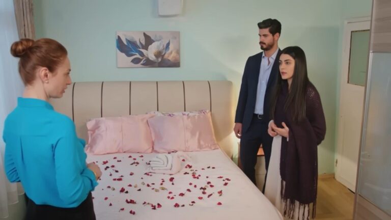 Hancer i Cihan stoją przy łóżku, które zostało obsypane płatkami czerwonych róż. Po drugiej stronie łóżka stoi Derya.