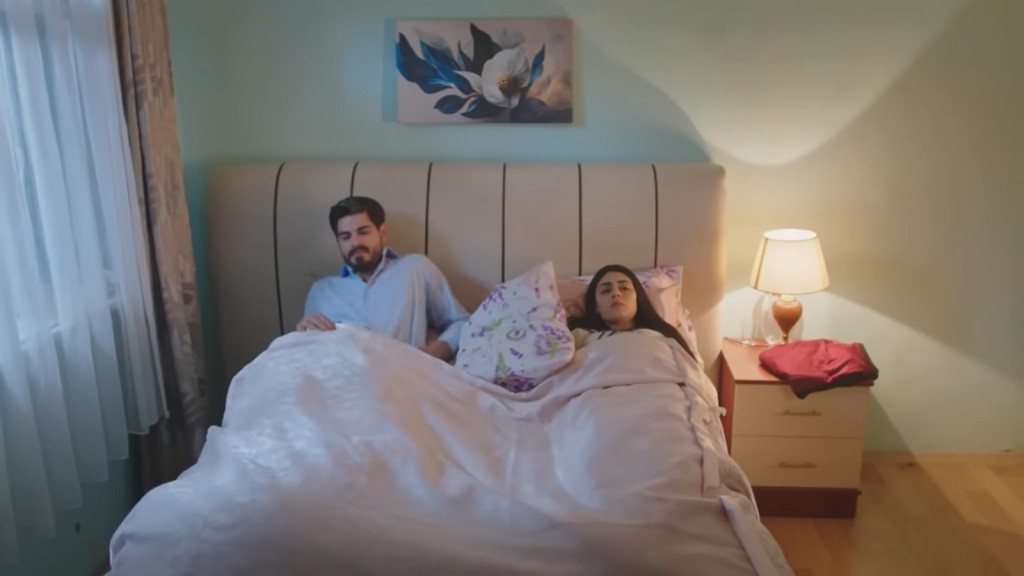 Cihan kładzie się w łóżku obok Hancer.